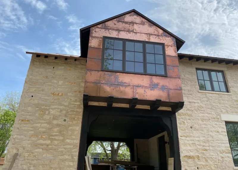 Copper metal panel facade on a stone building for Roof Repair in Wright