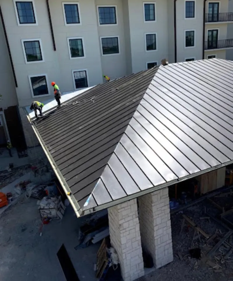 Crew installing standing seam metal roof panels on a commercial project in Wright